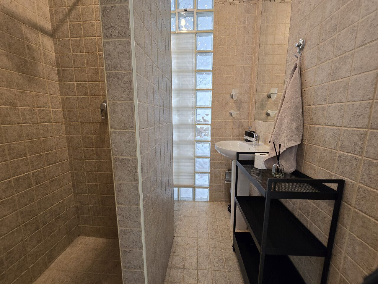 Ein Badezimmer mit Dusche, Waschbecken und Handtuchhalter.