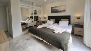 Un dormitorio moderno con una cama grande, mesitas de noche y un espejo.