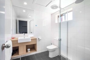 A modern bathroom with a glass shower enclosure, a white sink, and a toilet.