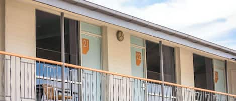Un immeuble avec des fenêtres numérotées, un balcon doté de rampes en métal et une horloge murale.