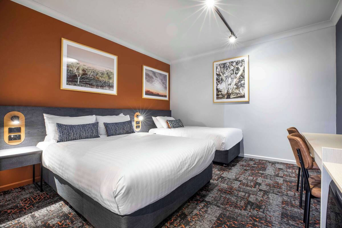 A hotel room with a large bed, two bedside tables, a desk, and chairs.