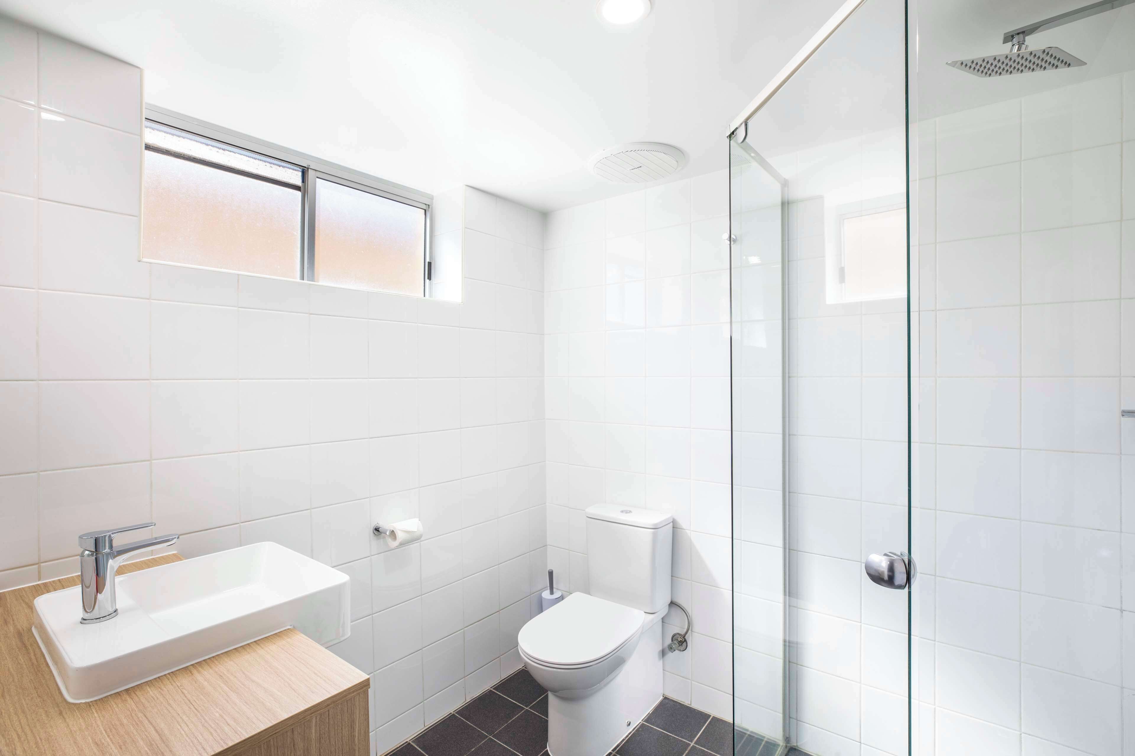 Un baño moderno con lavamanos, inodoro y cabina de ducha de vidrio.