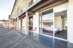 A hotel with a balcony, large sliding glass doors, and a visible bedroom with a bed and a chair. - Nightcap at Horse and Jockey Hotel Warwick (Warwick)