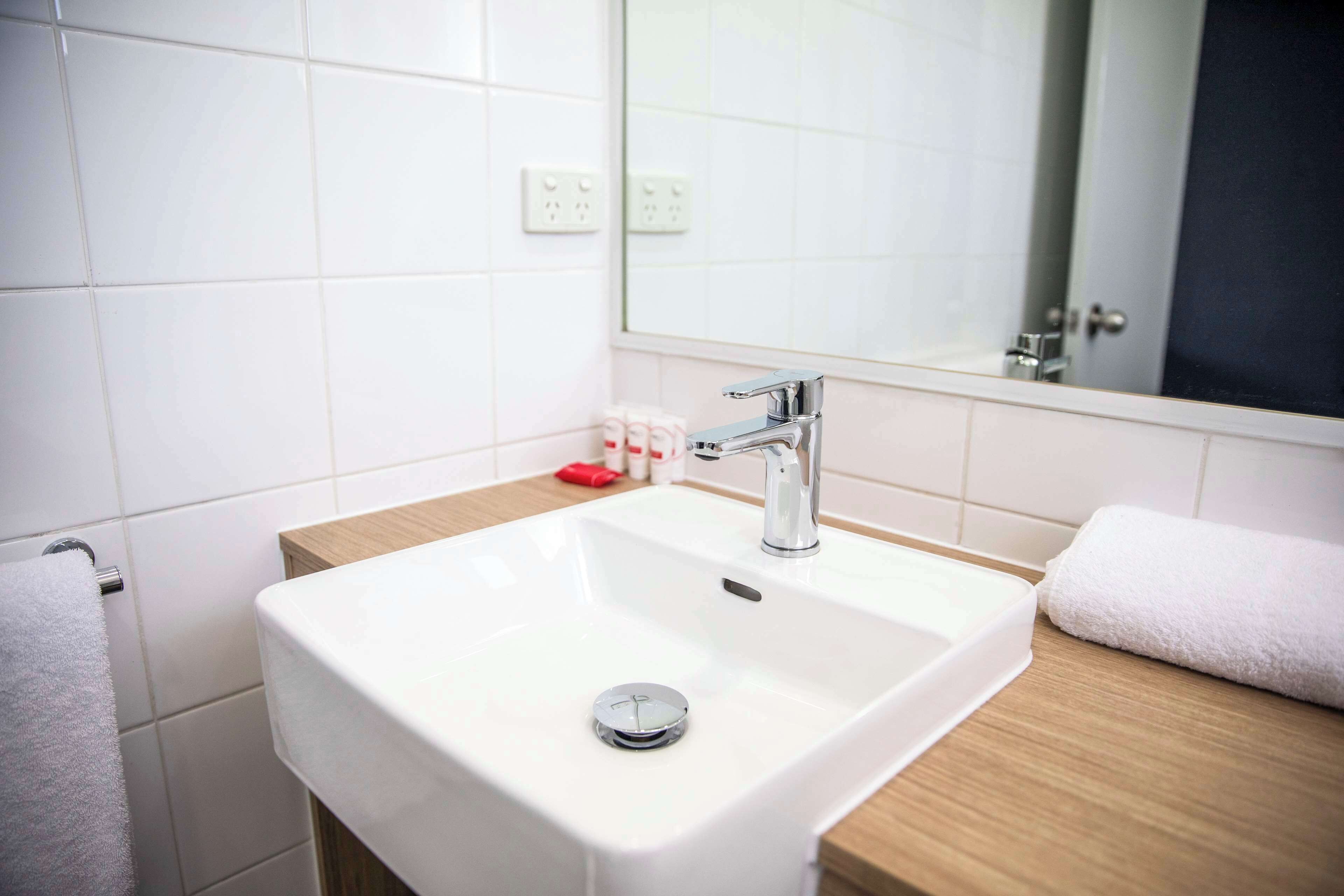 A bathroom with a white sink, a mirror, and a towel.