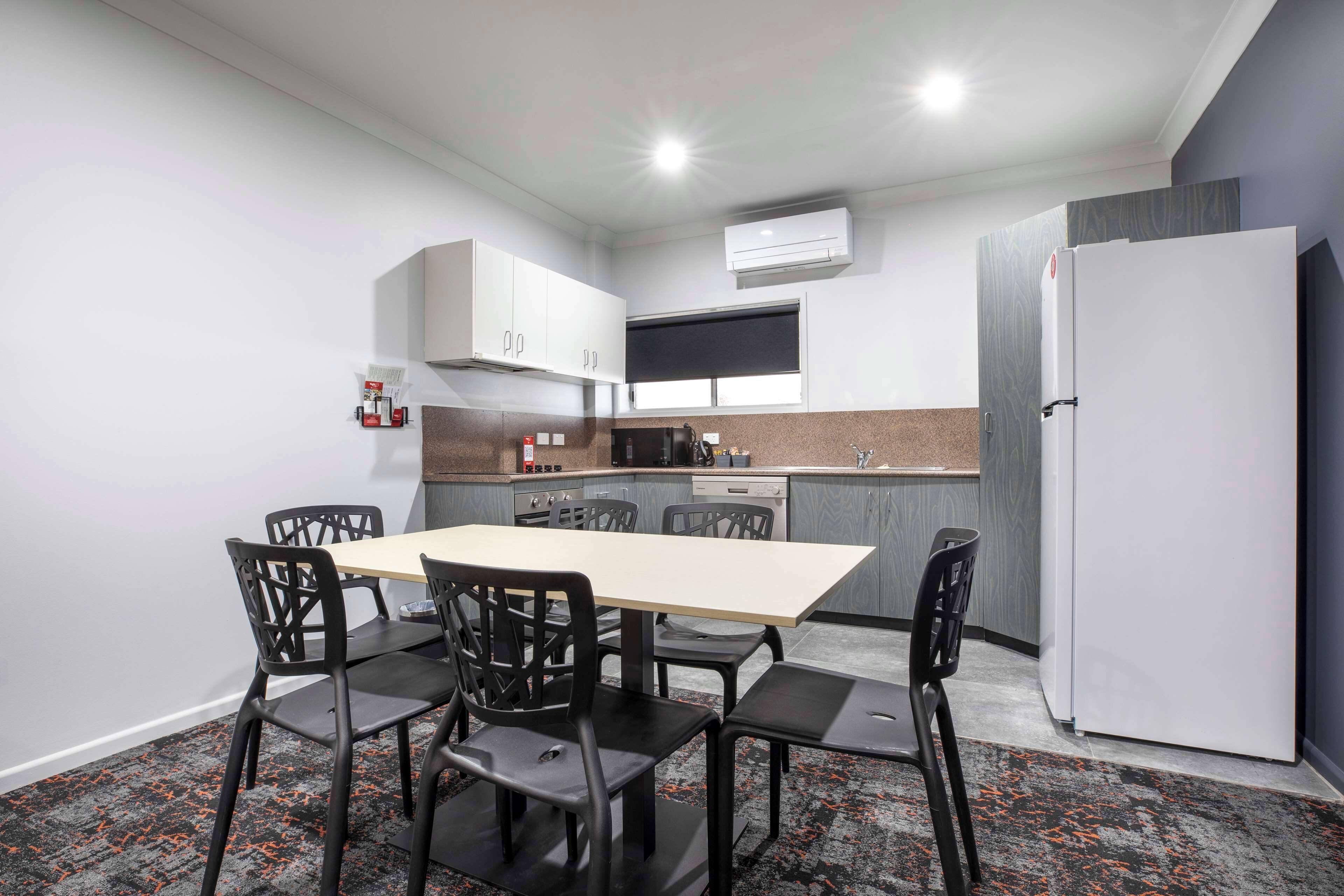 Une cuisine compacte avec un coin repas comprenant une table et des chaises, un réfrigérateur et un four à micro-ondes.
