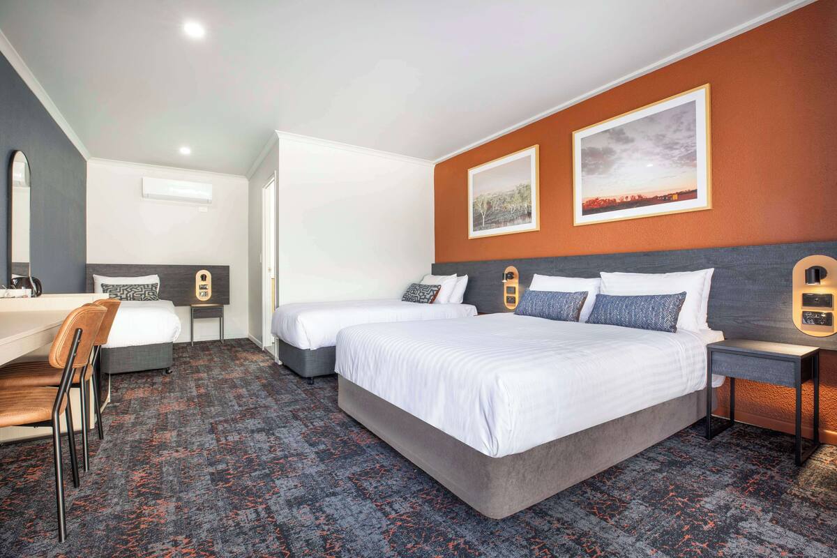 A hotel room with two beds, a desk, and a chair.