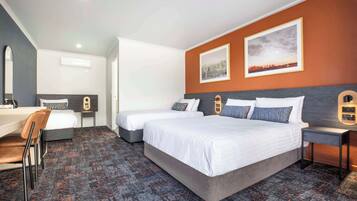 A hotel room with two beds, a desk, and a chair.