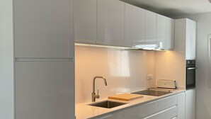 A modern kitchen with white cabinetry, a stainless steel sink, and a built-in oven. - L Estartit: Apartment/ flat - L''ESTARTIT (L'ESTARTIT)