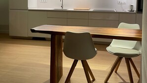 A modern kitchen with a central island, pendant lighting, and a dining area with a wooden table and two chairs. - L Estartit: Apartment/ flat - L''ESTARTIT (L'ESTARTIT)