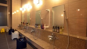 Un baño moderno con varios lavamanos, espejos y secamanos.