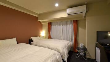 A hotel room with two beds, an air conditioning unit, a television, and a small table with a chair.