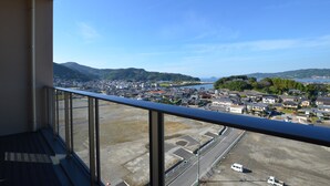 Un balcón con vistas a un paisaje urbano, que incluye un cuerpo de agua y montañas.