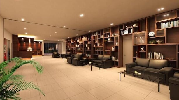 Una biblioteca amplia y moderna con sofás de cuero, una mesa de centro y una gran estantería llena de libros y objetos decorativos.