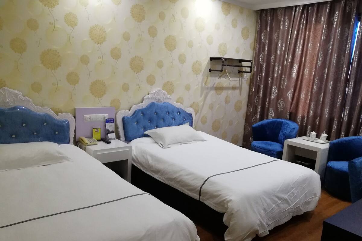 Une chambre d’hôtel avec deux lits, une table de chevet, une chaise et une petite table avec un plateau.