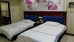 Habitación de hotel con dos camas, un cuadro de flores grande en la pared y un espejo.