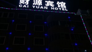 Exterior del hotel Cai Yuan con señalización iluminada y luces decorativas.