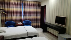 Habitación de hotel con dos camas, un escritorio, un televisor y un refrigerador pequeño.