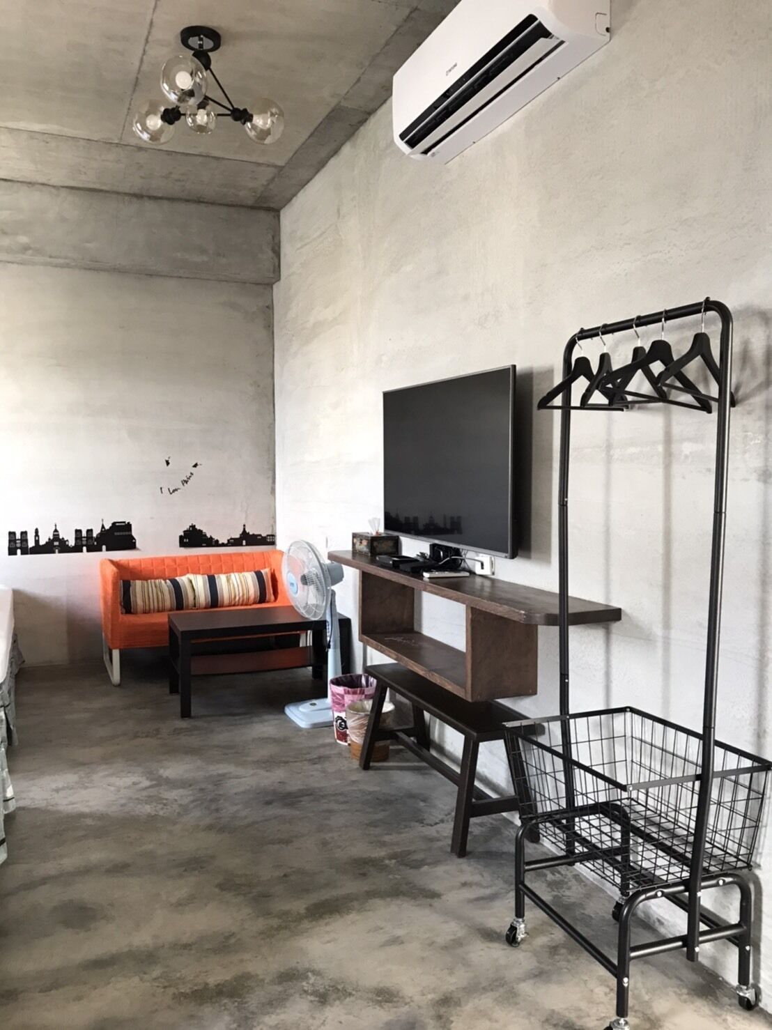 Una sala de estar con sofá, televisor y aire acondicionado instalado en la pared.