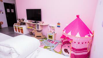 Een kinderkamer met een bed, een roze sprookjestent, een televisie en een klein boekenrek.