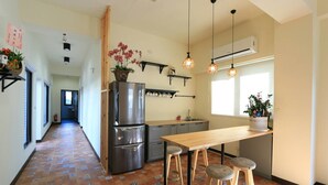 Una cocina moderna con un refrigerador de acero inoxidable, taburetes de madera e iluminación colgante.
