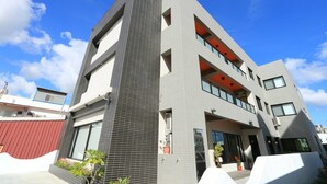 Un edificio moderno de varios pisos con una sección vertical destacada, ventanas grandes y balcones.