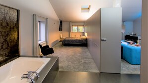 A modern bedroom with a large bed, a window, and a skylight.