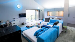 A modern hotel room with a large bed, a sofa, a small table, a TV, and a balcony with a view.