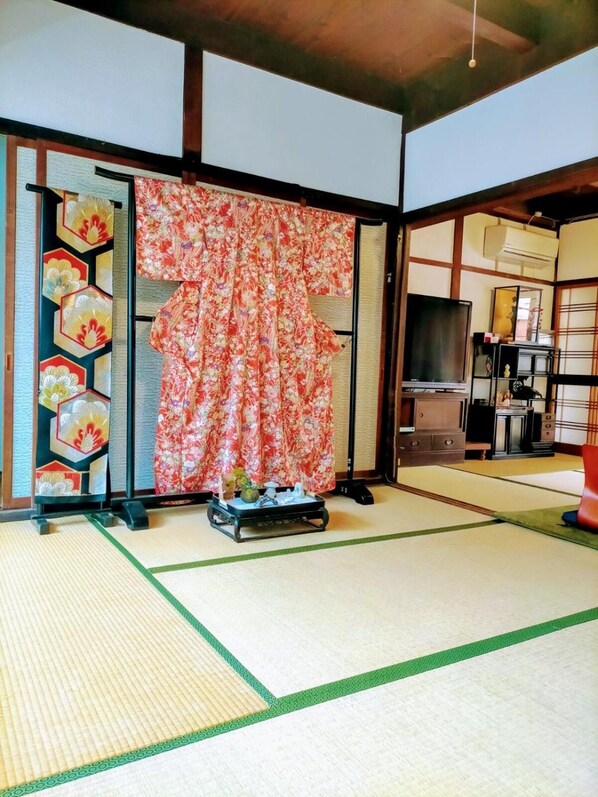 Une pièce de style japonais traditionnel, avec un sol recouvert de tatamis, un paravent shoji orné de motifs floraux et un téléviseur.
