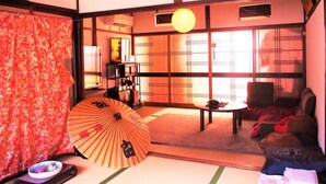 Ein traditioneller japanischer Raum mit Tatami-Boden, einem niedrigen Tisch und einem großen Fächer.