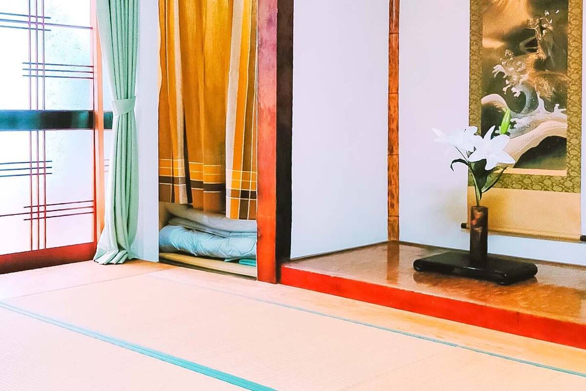 Een kamer met tatami matten, een verschuifbare shoji-scherm, een futonbed en een traditioneel Japans schilderij.