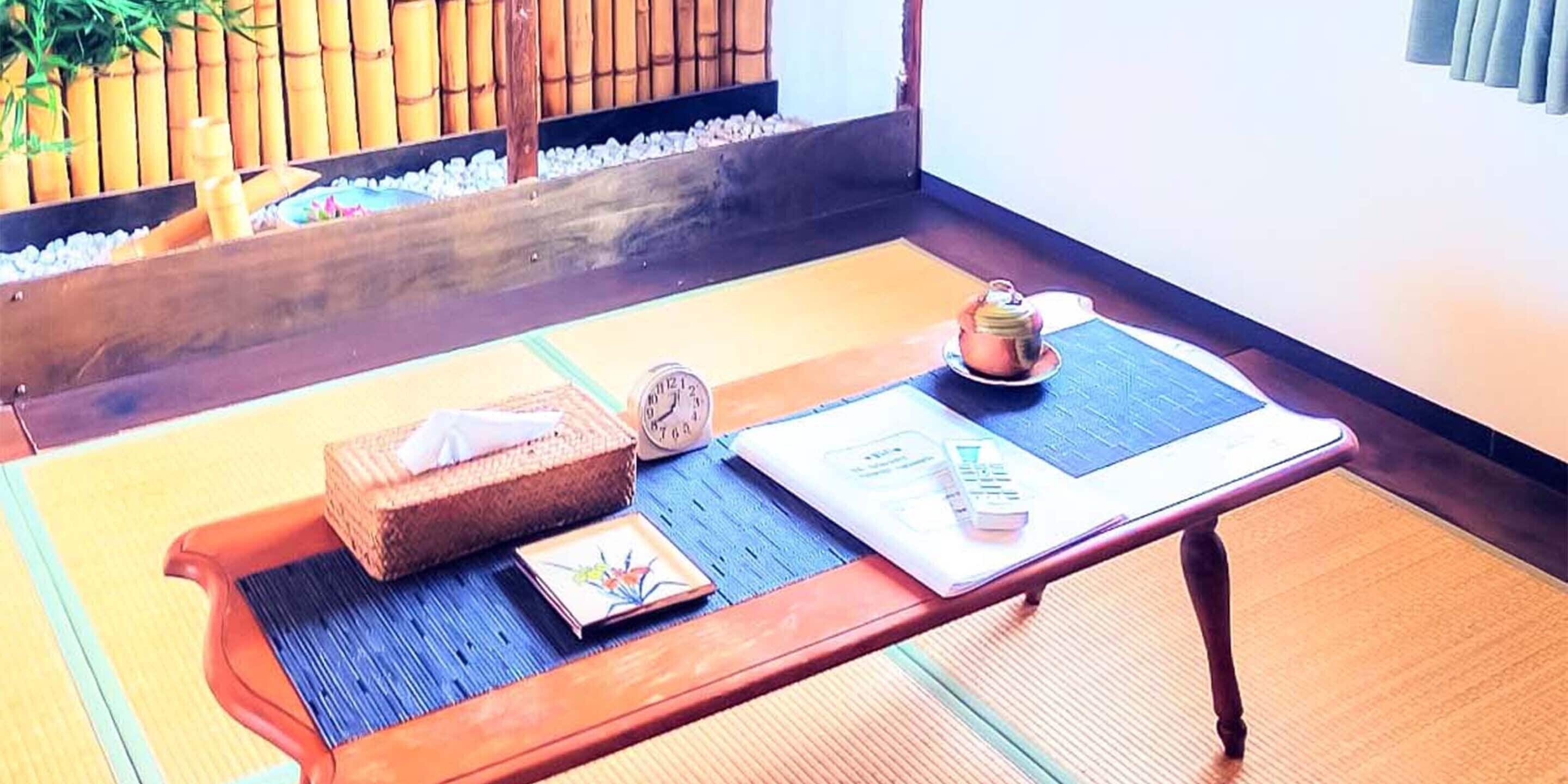 A tatami mat room with a wooden table, a small clock, a teapot, and a box.