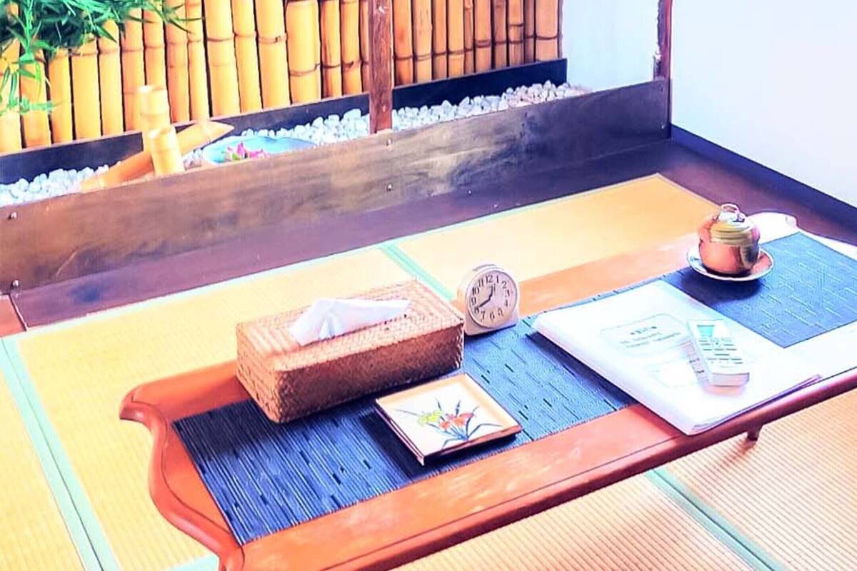 Een kamer met tatami matten, een houten tafel, een klein klokje, een theepot en een doos.