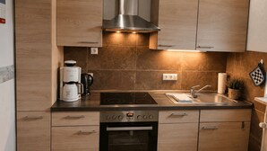 A modern kitchen with wooden cabinets, a stainless steel range hood, a built-in oven, and a coffee maker. - Top vacation home,7 p.,sauna,2 baths,WLAN,fireplace,beach kitchen,terrace,dog,playground (Dornum)