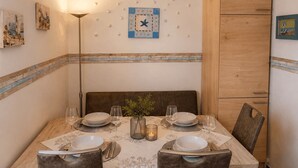 A dining room with a wooden table set for four, a wall clock, and a cabinet. - Top vacation home,7 p.,sauna,2 baths,WLAN,fireplace,beach kitchen,terrace,dog,playground (Dornum)