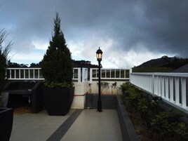 Un espacio al aire libre techado con barandilla, una farola y una planta grande en maceta.
