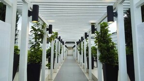 A covered walkway with white pillars and black lights, lined with potted plants. - Misty Forest II - 9 Pax Next To Night Market (Tanah Rata)