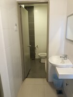 Un baño con inodoro, lavabo y zona de ducha.