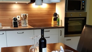 A wooden dining table with a bottle of wine, a glass of water, and a glass jar with seashells. - The best time on the largest island of Germany enjoy. (Ummanz/Waase)