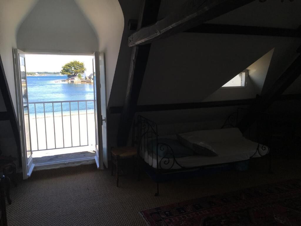 Quarto com cama, vista para o mar e varanda.