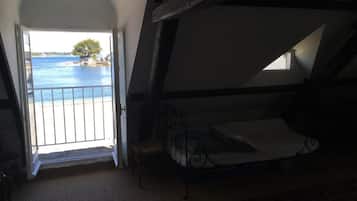 Quarto com cama, vista para o mar e varanda.