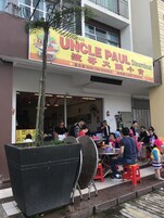 Un ristorante chiamato "Uncle Paul Steamboat" con posti a sedere all'aperto e un grande cartello pubblicitario del suo menu.