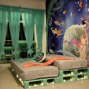 A room with a bed featuring striped bedding, a mural of a mermaid, teal curtains, and a small table with chairs. - Blue Romance 2 Cameron Highlands (Tanah Rata)