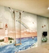 Un murale raffigura un faro, un'altalena e una barca a vela su una spiaggia.