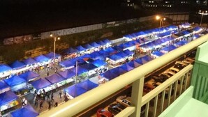 Ein nächtlicher Markt im Freien mit mehreren blauen Zelten und einem Fußweg.