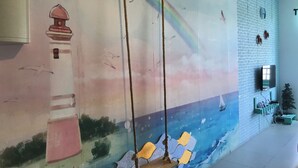 Ein Wandbild mit einem Leuchtturm, Schaukeln und einem Regenbogen.