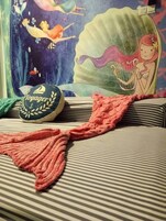 Un divano a righe con una coperta a forma di coda di sirena e un cuscino a tema Voyager.