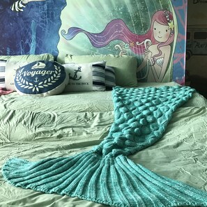A bed with a teal knitted mermaid tail, pillows with nautical designs, and a poster of a mermaid. - Blue Romance 2 Cameron Highlands (Tanah Rata)