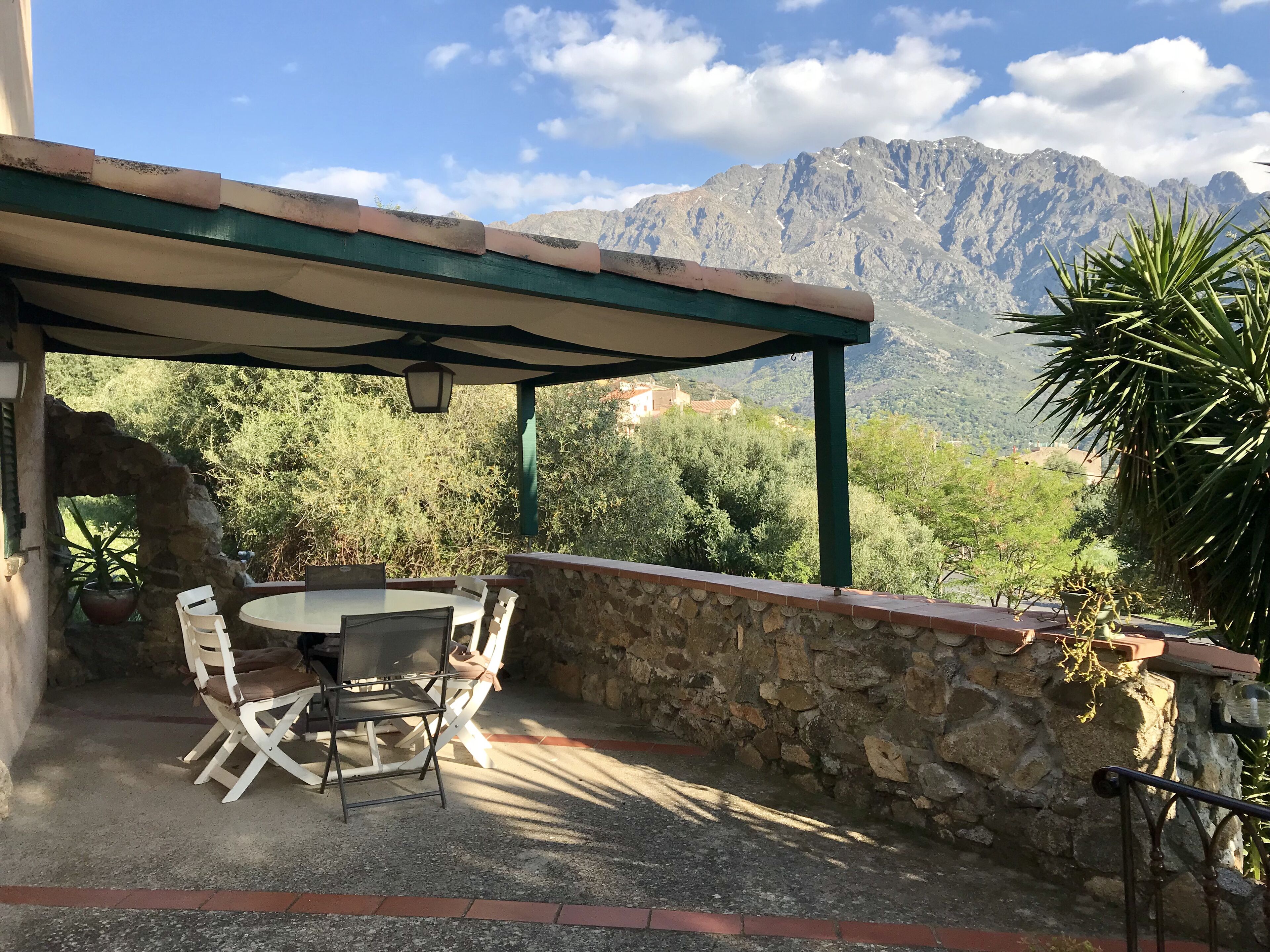 A patio with a table and chairs, a stone wall, and a view of mountains.