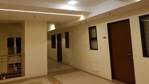 Un pasillo con una escalera, puertas y una barandilla.