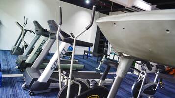 Ein Fitnessraum mit mehreren Laufbändern, Crosstrainern und einem stationären Fahrrad.